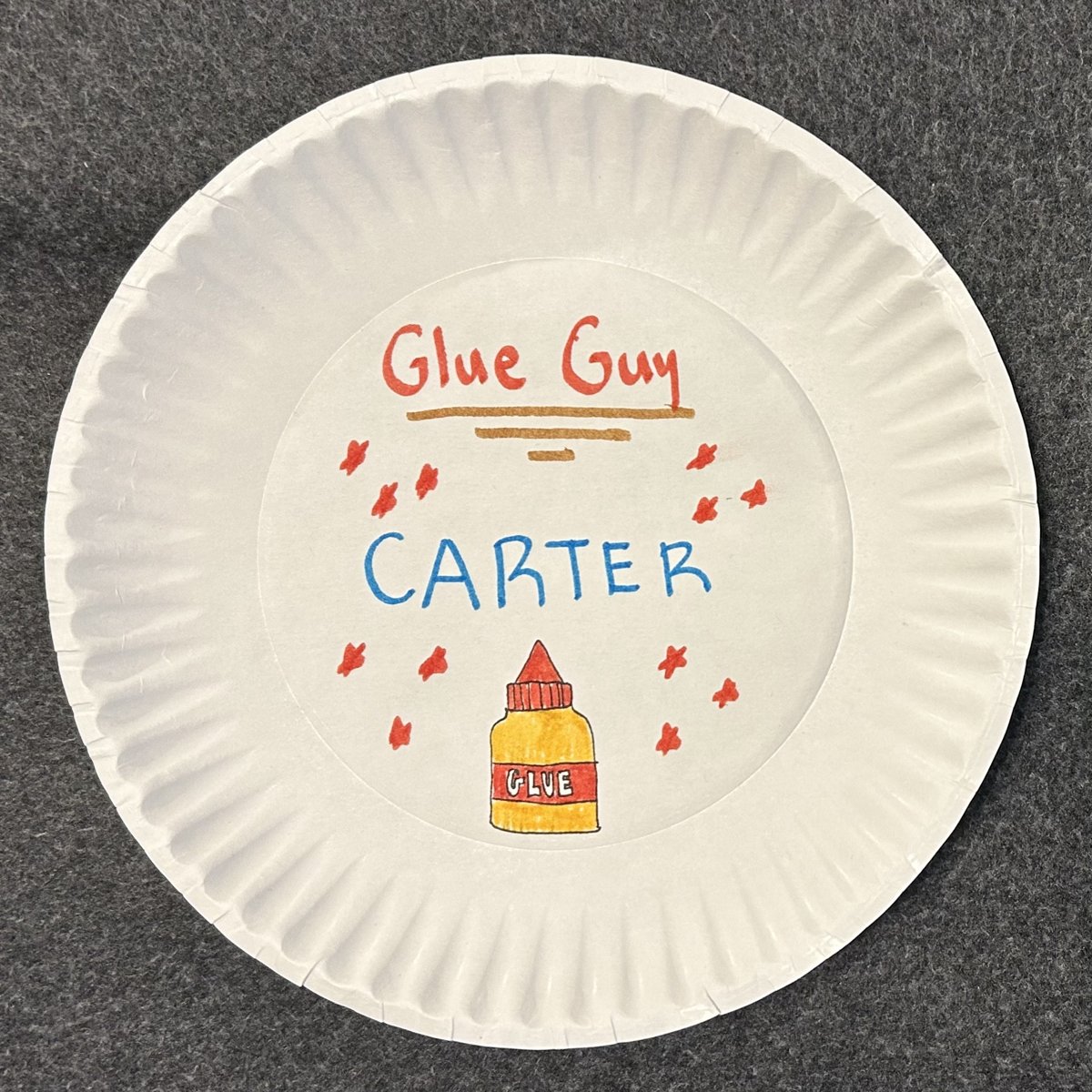 Paper-plate award reading "Glue Guy - Carter" with a hand-drawn glue bottle