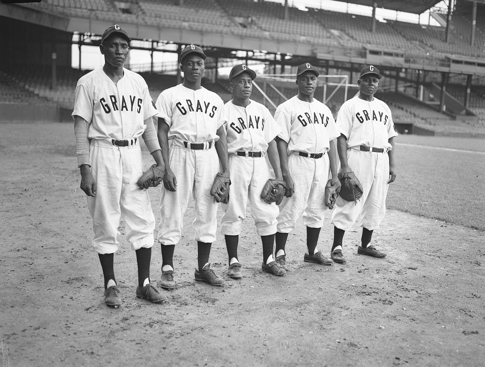 Five Washington Homestead Grays players in uniform standing on the field at Griffith Stadium, 1947