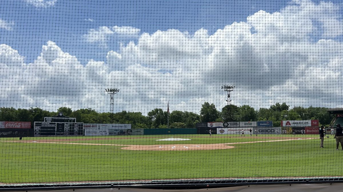 Rickwood Field through the netting: scoreboard, light towers, summer sky